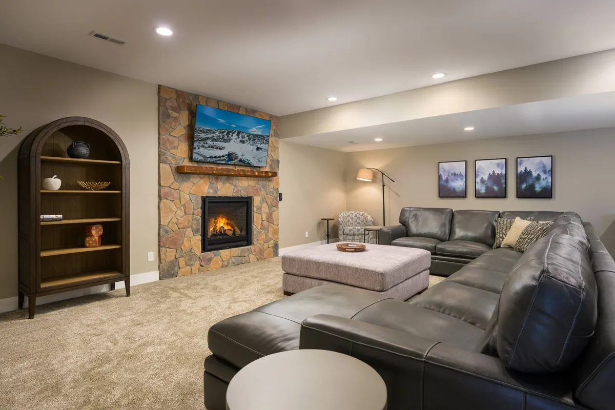A spacious living area with a sectional sofa, fireplace, and coffee table, creating a warm and inviting space for gatherings. The setup is ideal for relaxing evenings, whether enjoying quiet time or hosting friends (and pets).