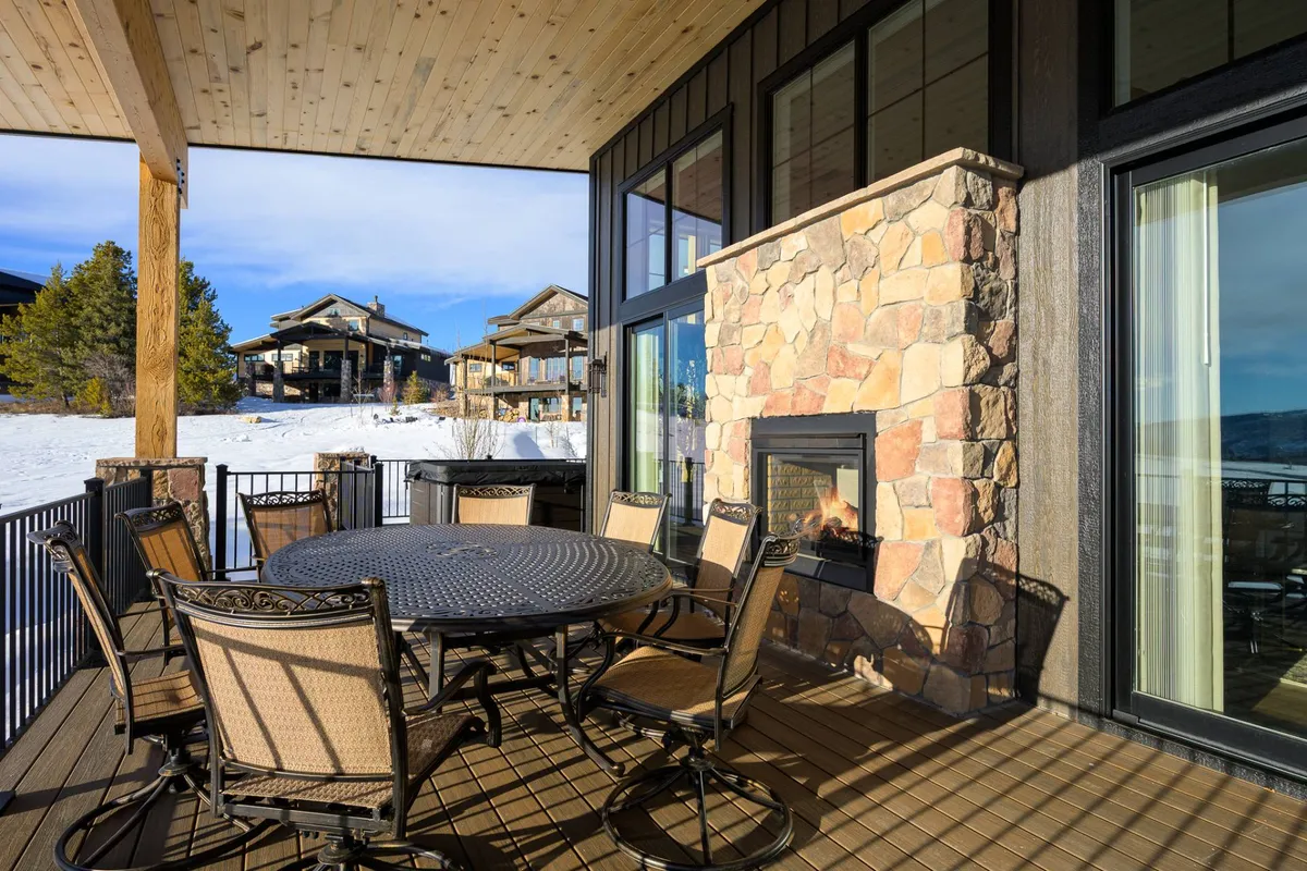 An inviting outdoor dining setup featuring a table, fireplace, and the surrounding landscape. The space is arranged for al fresco meals, socializing, and enjoying the scenery, with the fireplace adding warmth and ambiance for evening or wintertime events.