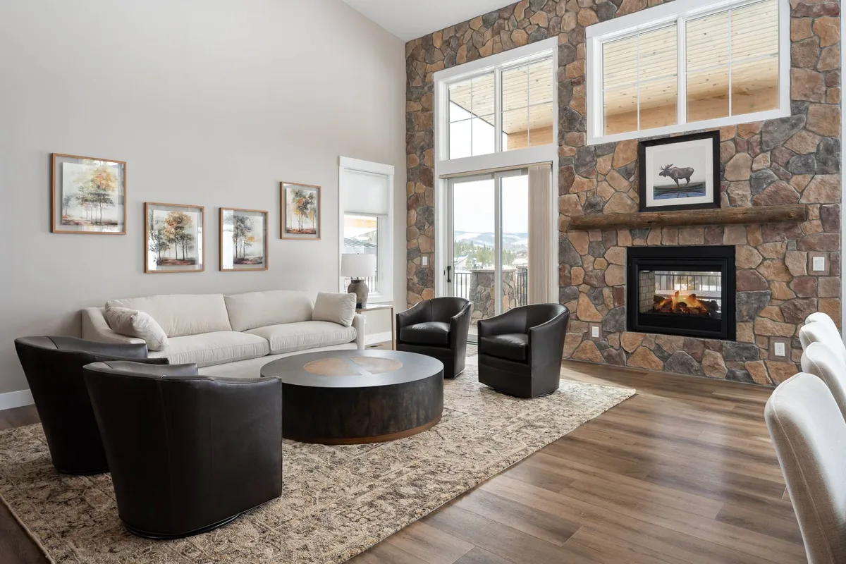 A welcoming living room featuring a cozy seating arrangement around a stone fireplace, with soft lighting and natural textures. The arrangement invites relaxation and socializing, suggesting a comfortable space for guests and their pets to unwind after a day outdoors.