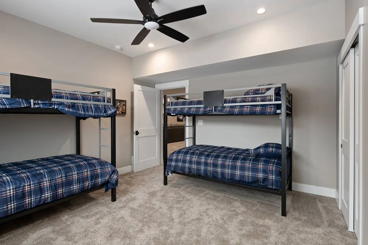 Bunk beds adorned with plaid bedding create a fun, relaxed sleeping area ideal for families or groups, with a ceiling fan and cozy atmosphere perfect for late-night chats and games.